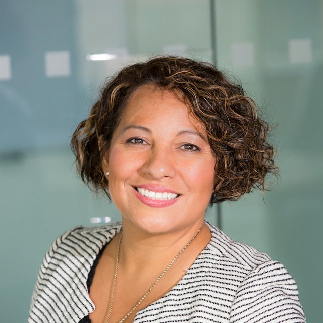 Smiling woman with short curly brown hair and a striped top