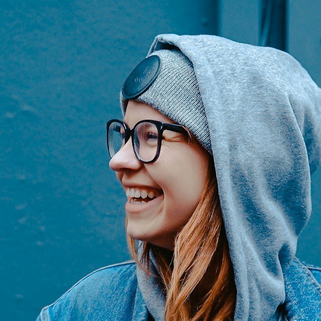 Laughing woman in glasses and a gray hoodie